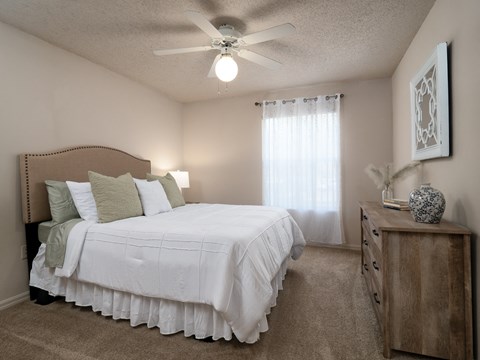 a bedroom with a large white bed and a ceiling fan